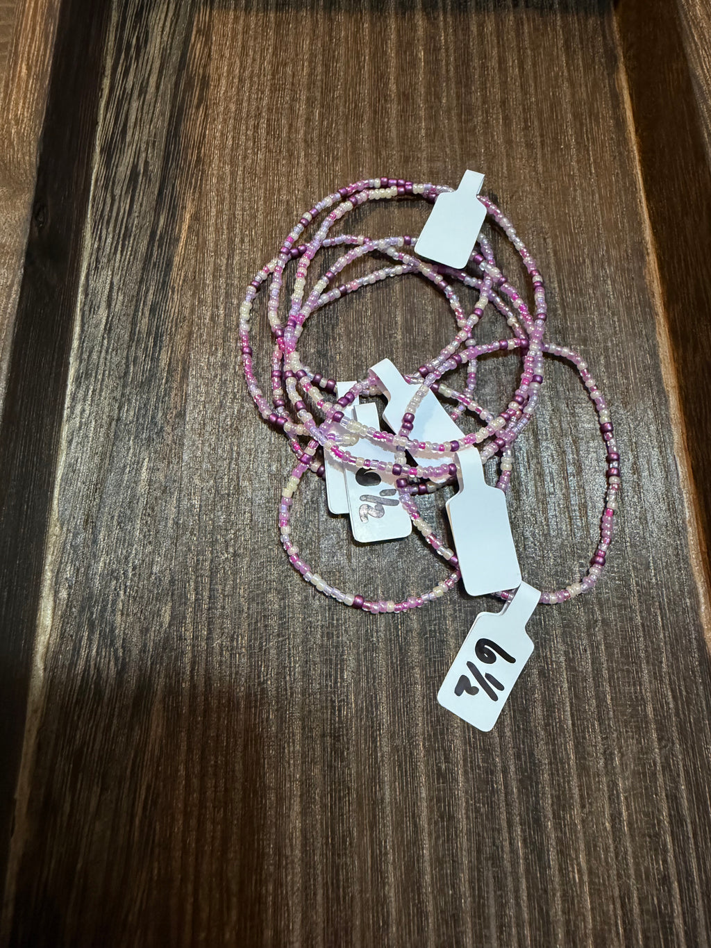 A pile of handmade beaded bracelets in the Tower Dreams color scheme with the size tags on them.