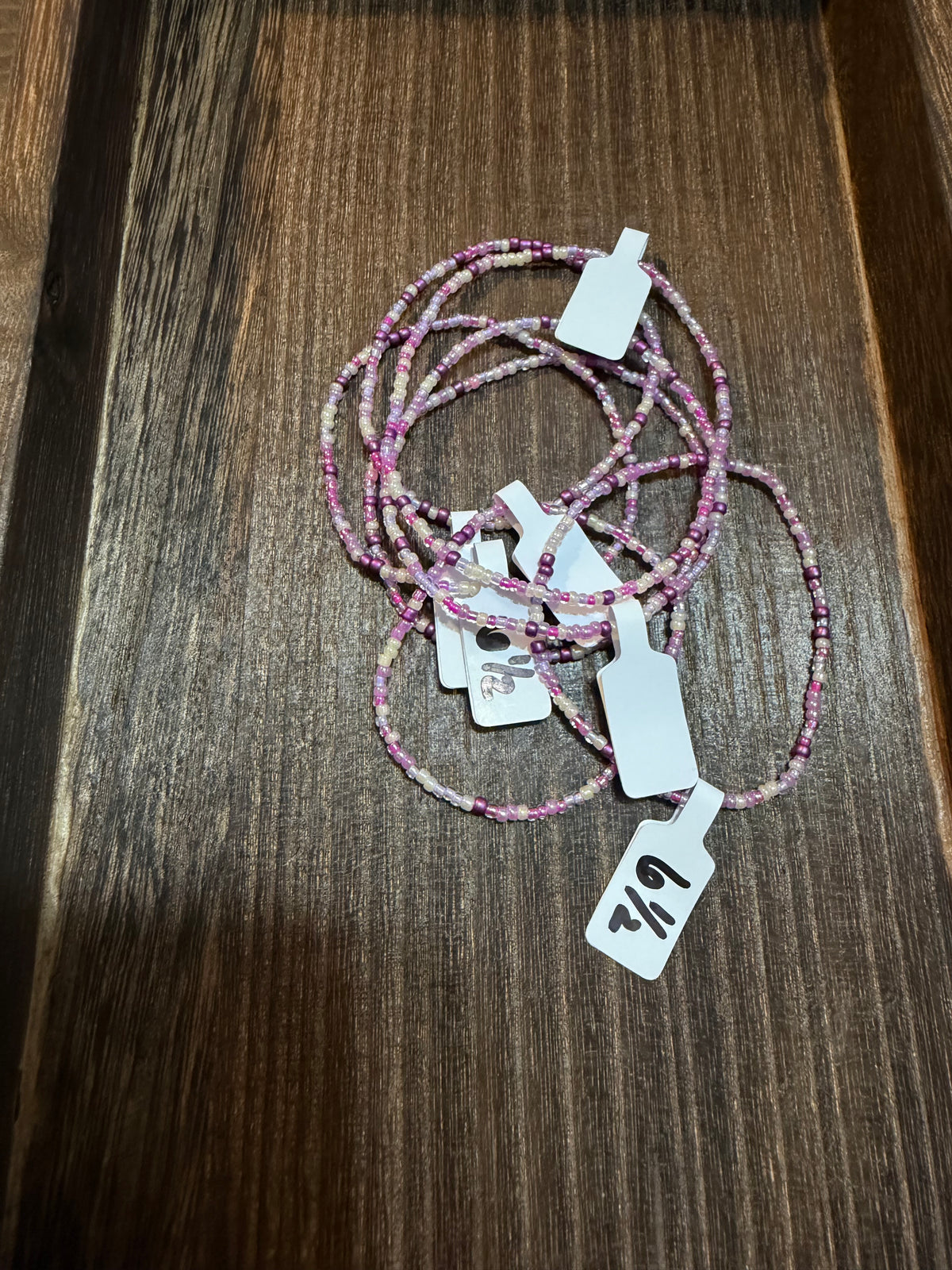 A pile of handmade beaded bracelets in the Tower Dreams color scheme with the size tags on them.