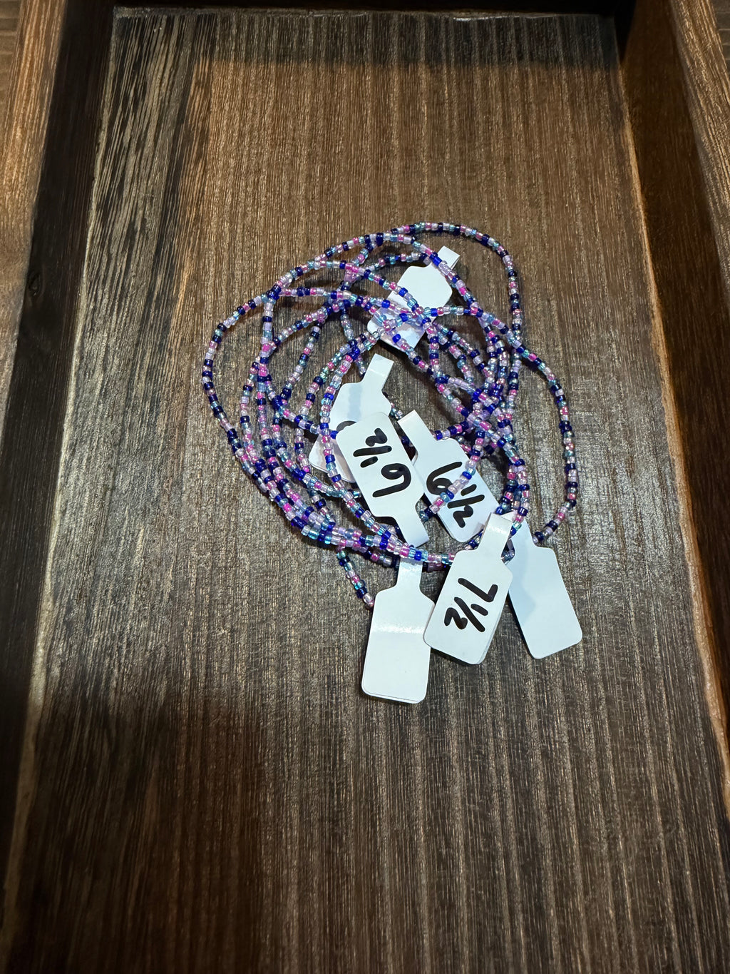 A pile of handmade beaded bracelets in the Mermaid color scheme with the size tags on them.