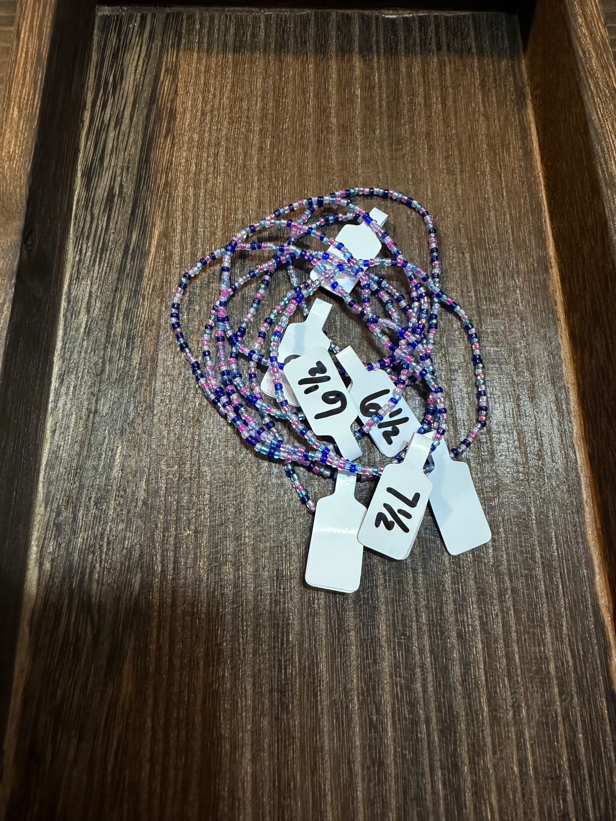 A pile of handmade beaded bracelets in the Mermaid color scheme with the size tags on them.