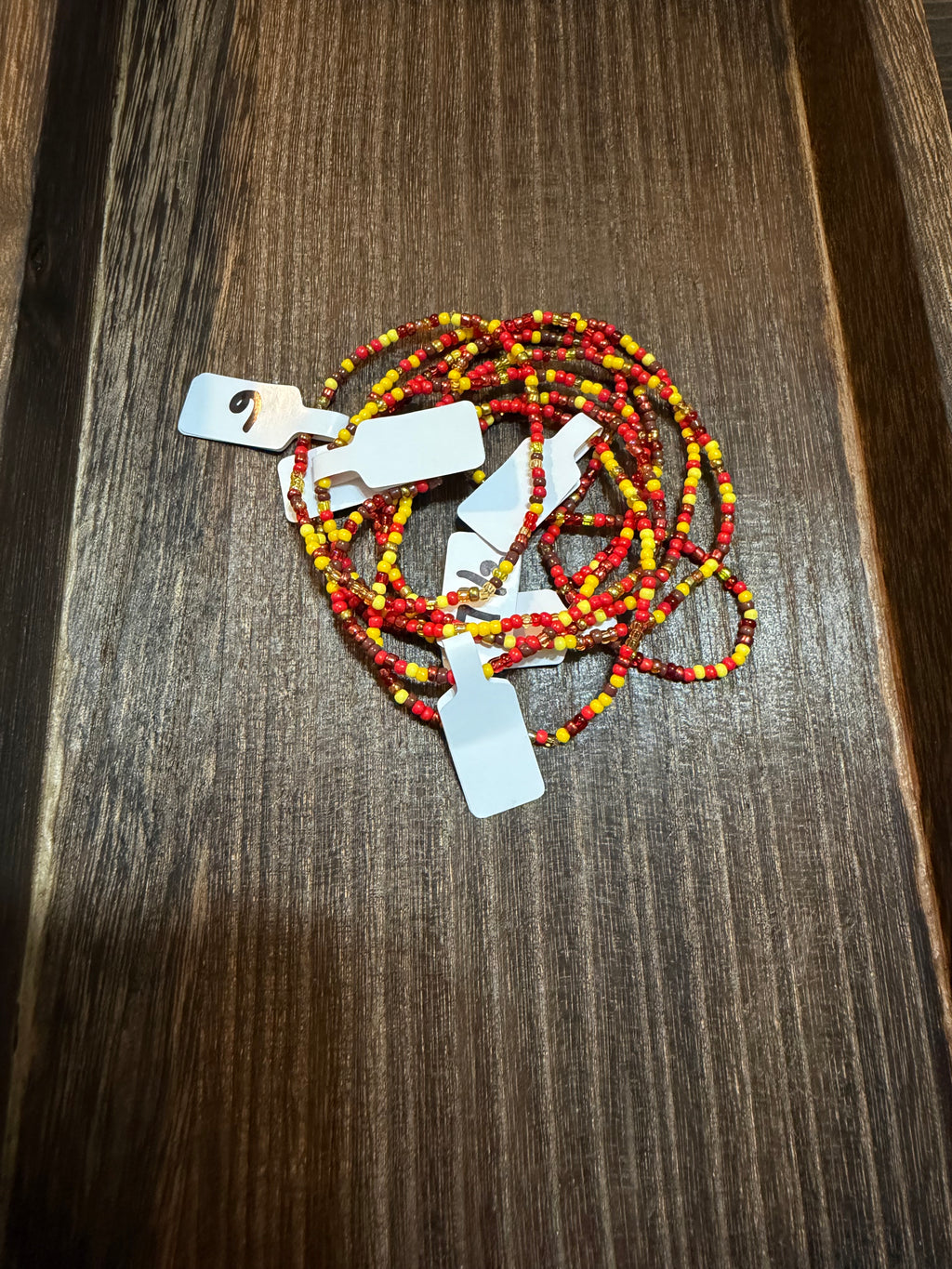 A pile of handmade beaded bracelets in the Give Thanks color scheme with the size tags on them.