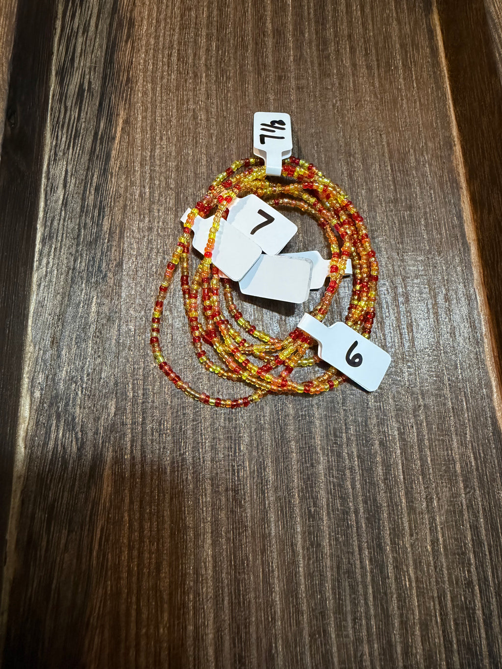 A pile of handmade beaded bracelets in the Falling Leaves color scheme with the size tags on them.