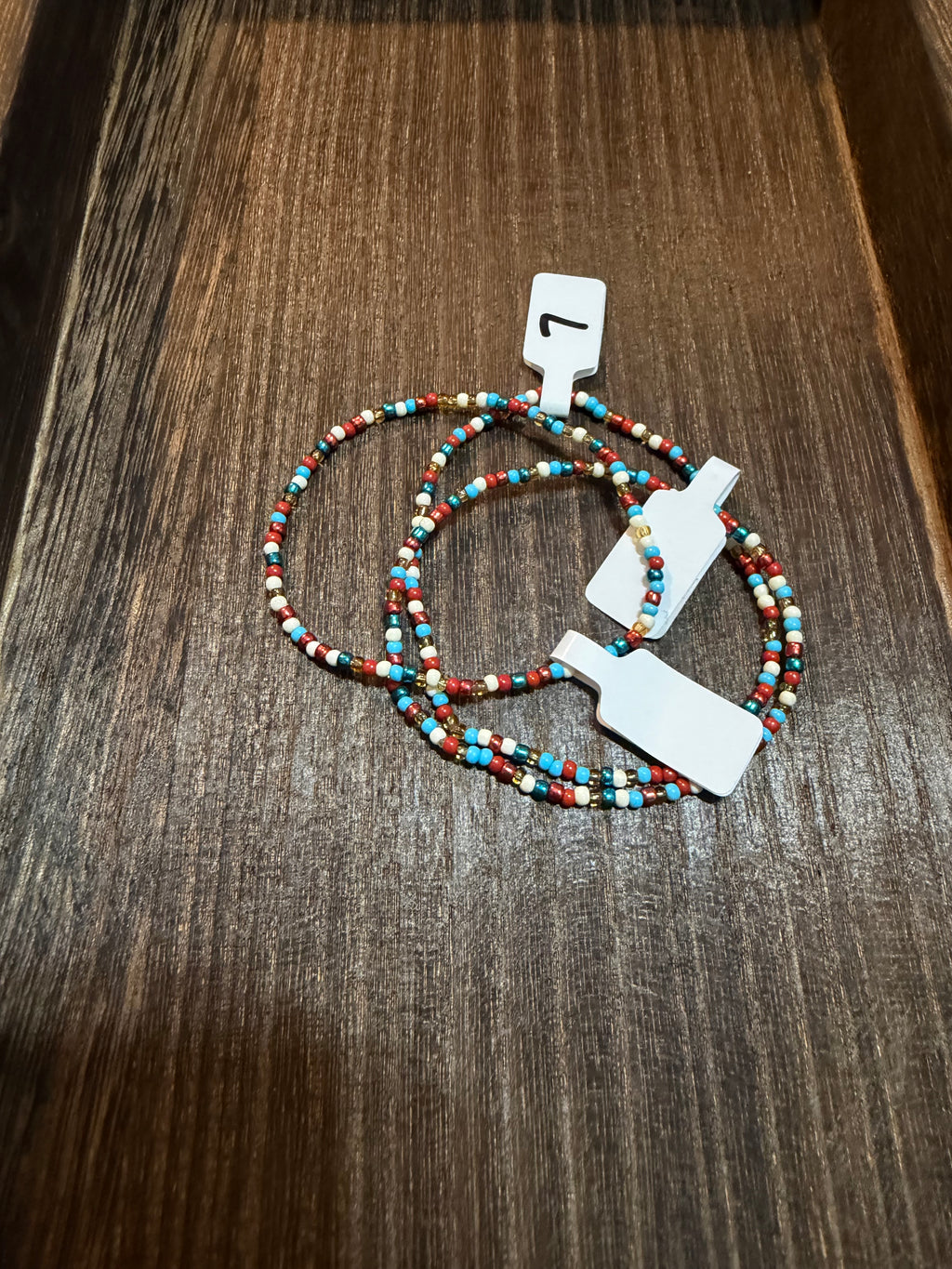A pile of handmade beaded bracelets in the Colors of the Wind color scheme with the size tags on them.