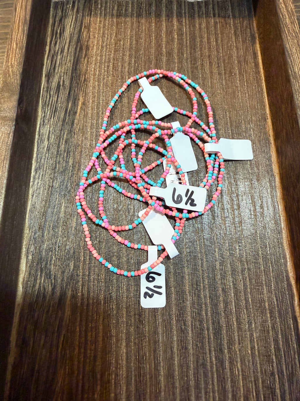A pile of handmade beaded bracelets in the Southwest color scheme with the size tags on them.