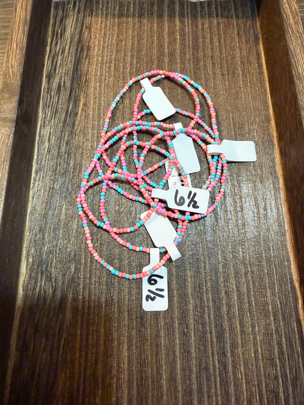A pile of handmade beaded bracelets in the Southwest color scheme with the size tags on them.