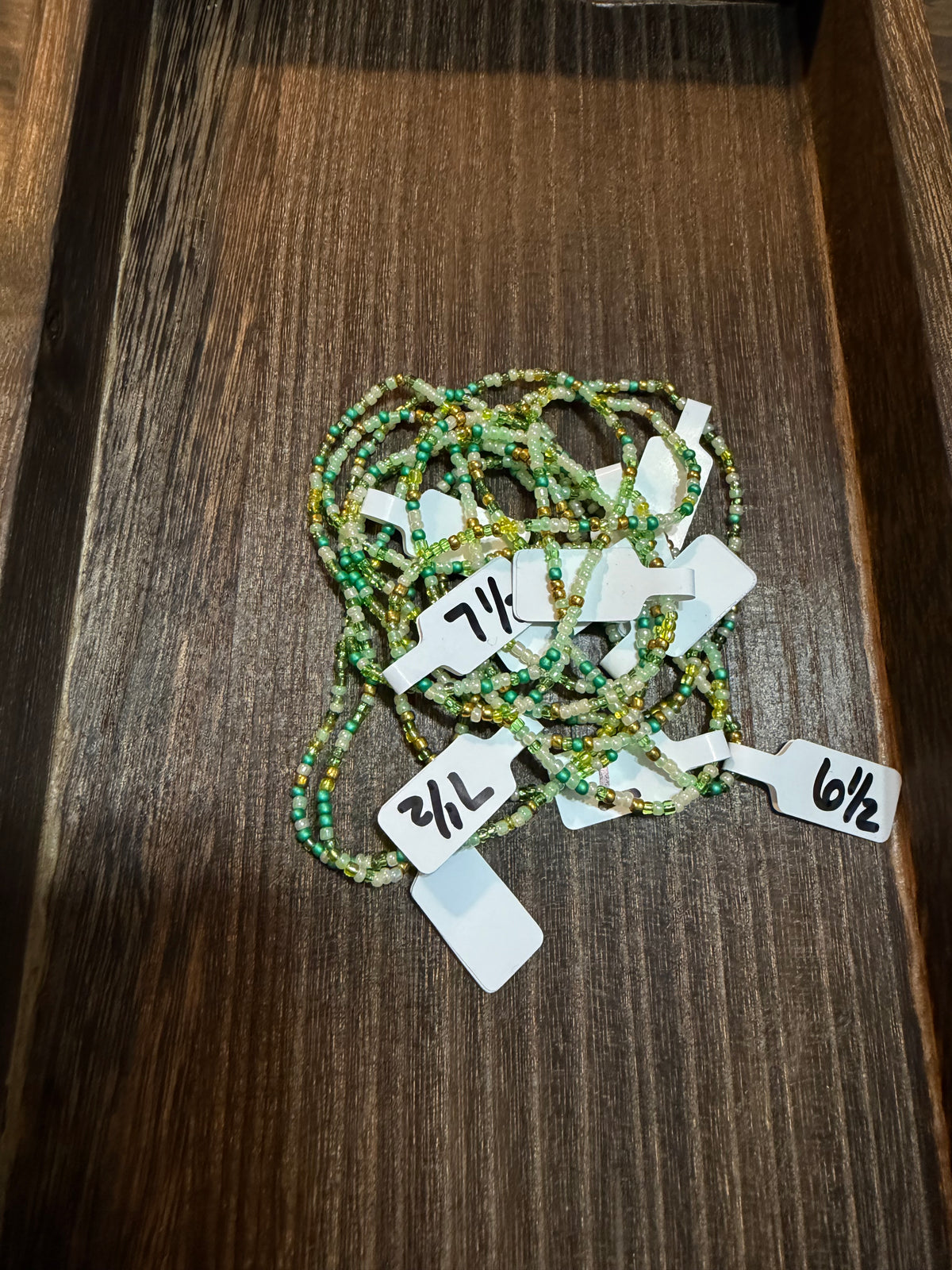 A pile of handmade beaded bracelets in the Bayou color scheme with the size tags on them.