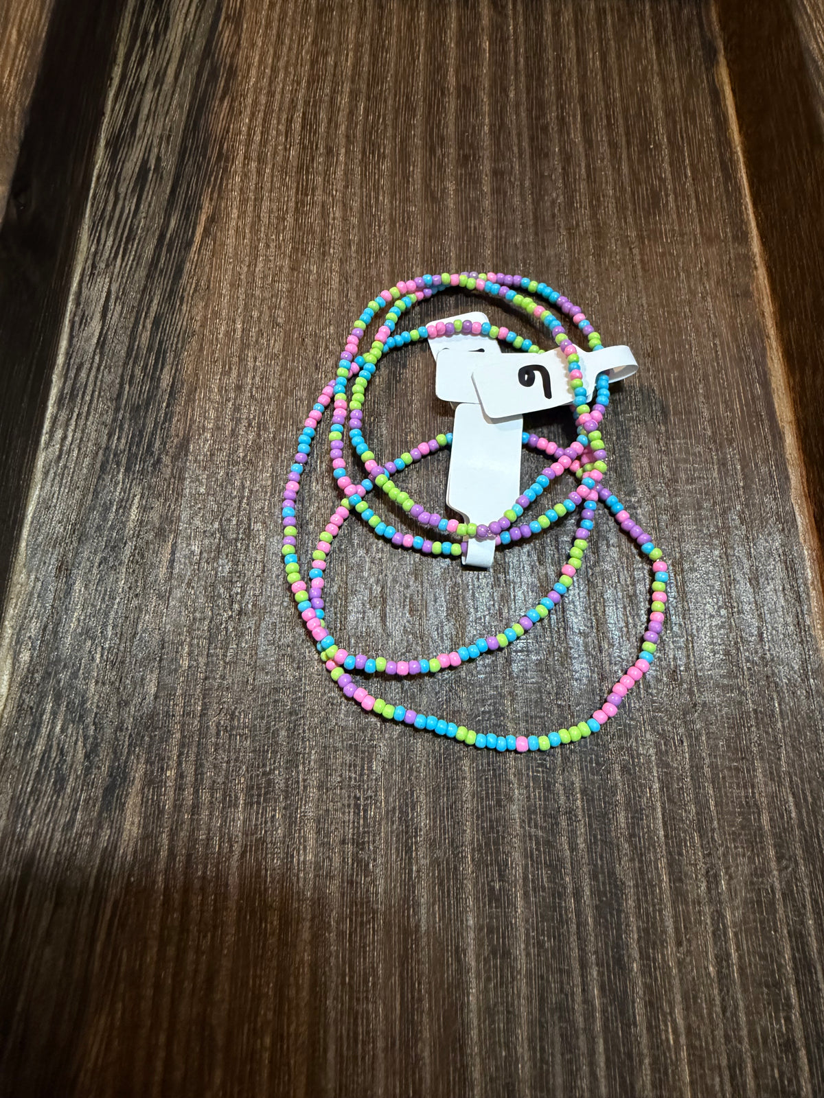 A pile of handmade beaded bracelets in the Electric color scheme with the size tags on them.