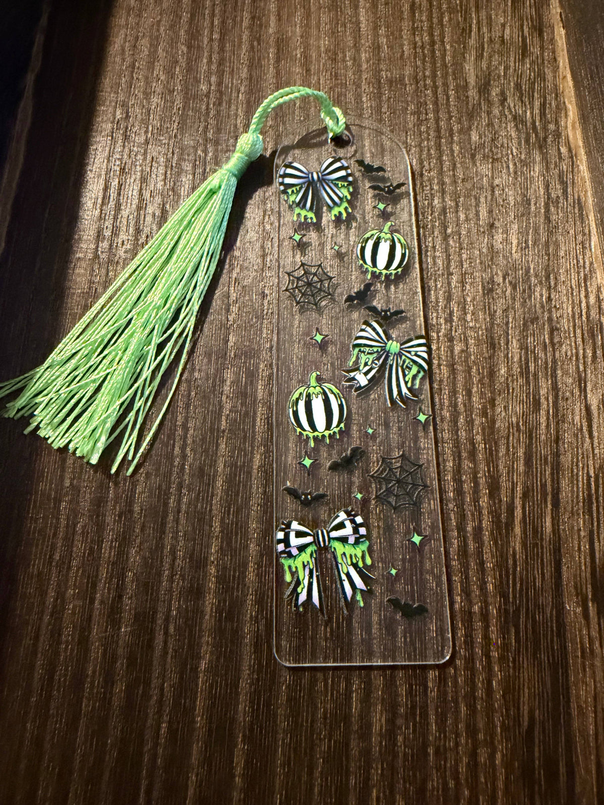 Halloween acrylic bookmark with green, black, and white spooky design inspired by a certain someone with a matching bright green tassel.