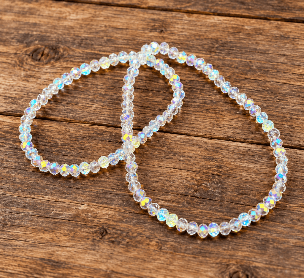 Two beaded bracelets with iridescent, faceted clear beads arranged on a rustic wooden surface.