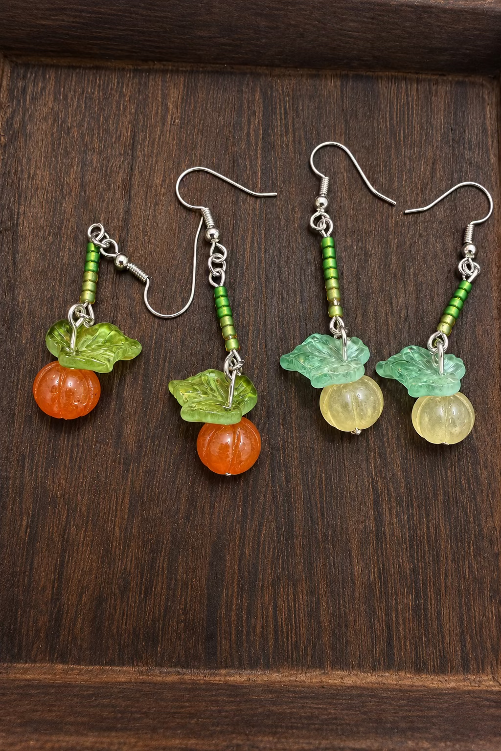 Two pairs of stone pumpkin earrings with glass accent beads and glass leaves.